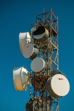 A very tall tower with lots of white dishes on top of it