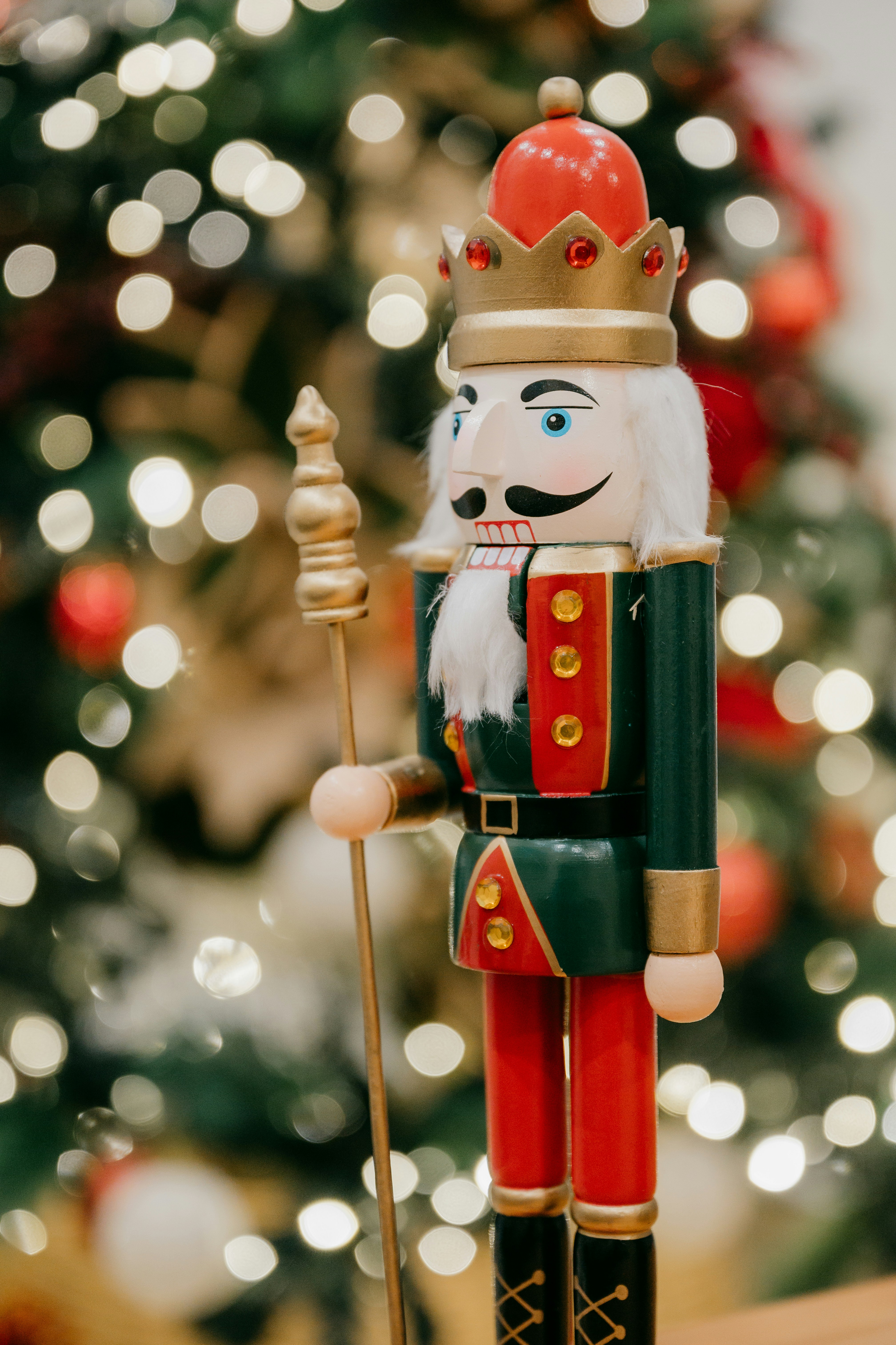 A nutcracker is standing in front of a christmas tree