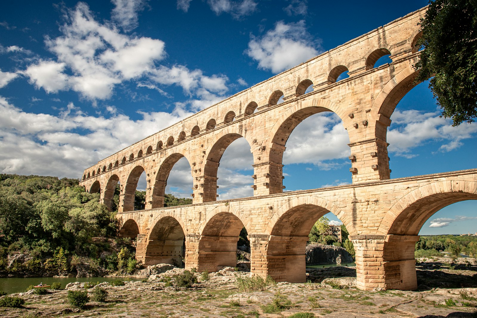 The three tiers of arches of the Roman Pont du Gard aqueduct under a blue sky with white clouds