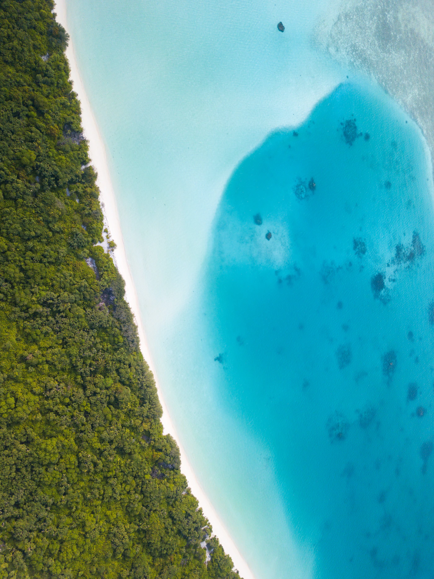 Aerial view of a brilliant blue lagoon within a tropical island in the Maldives