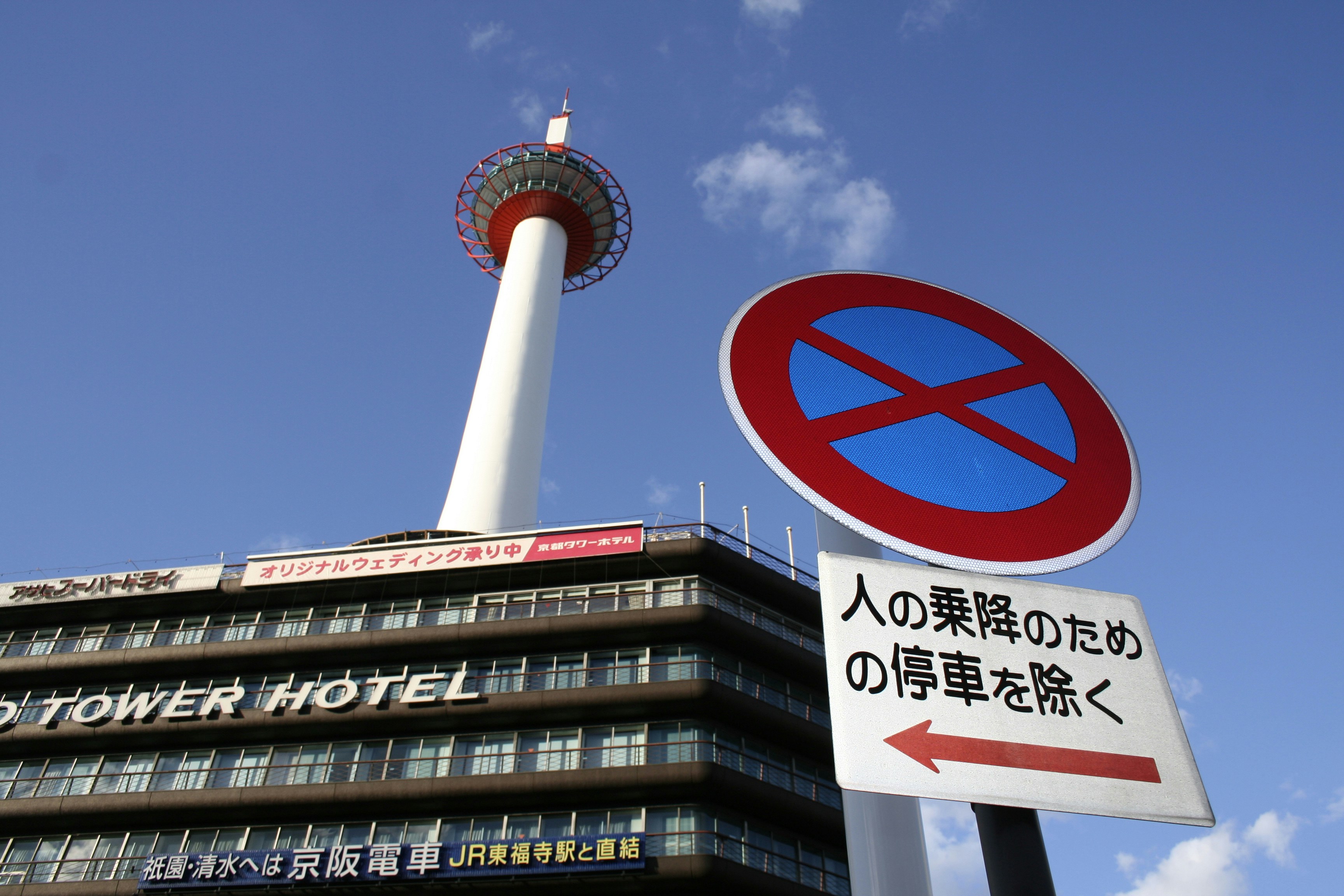 Confused tourist holding phone with Japanese hospital sign in background