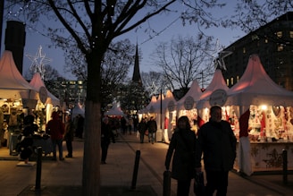 A group of people walking down a street next to tents
