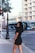 A woman in a short black dress standing on a sidewalk