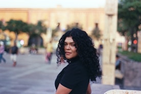 A woman standing on a sidewalk with a skateboard