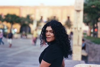 A woman standing on a sidewalk with a skateboard