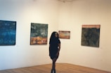 A woman standing in a room with paintings on the wall