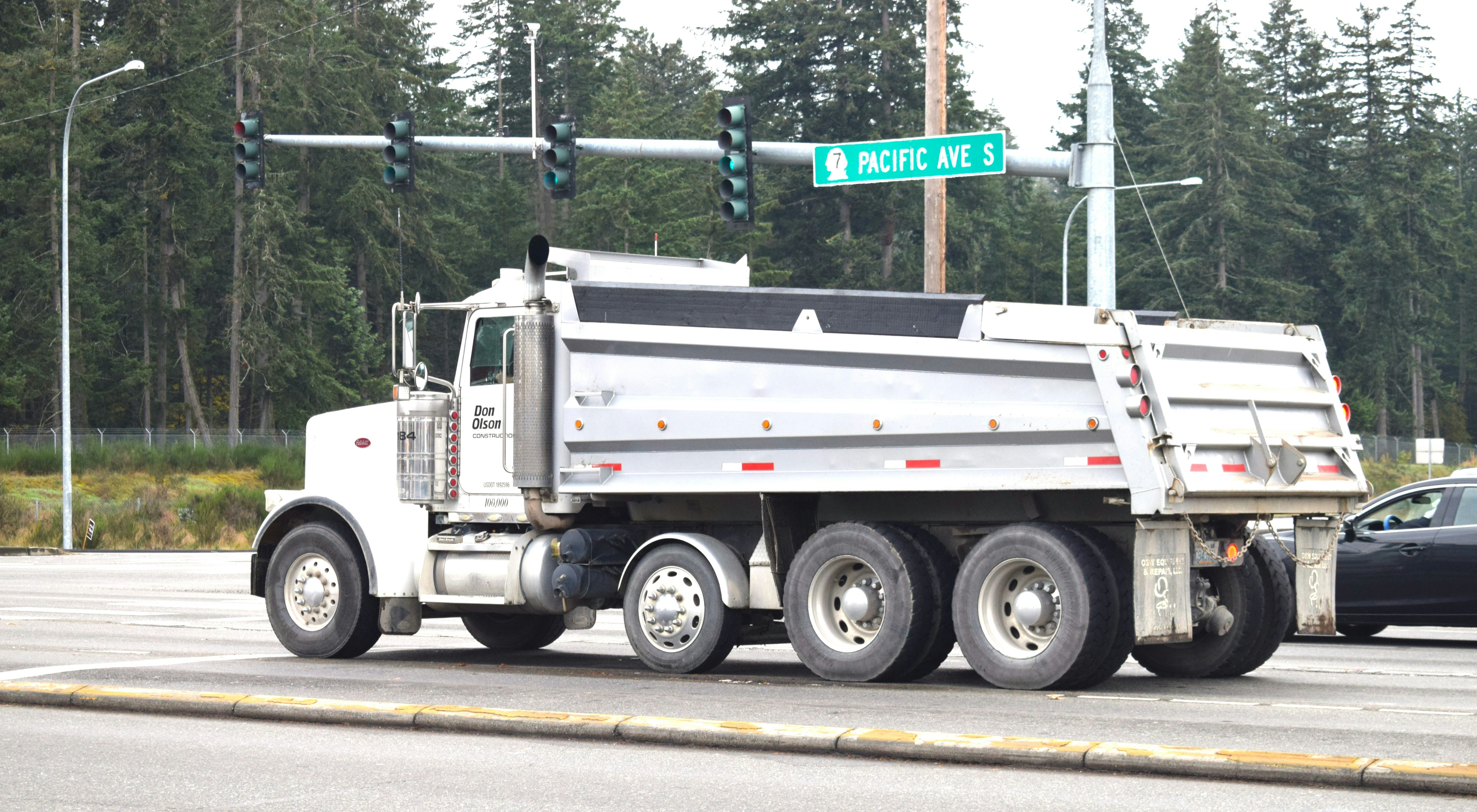 A white dump truck driving down a street next to a traffic light (Photo by fr0ggy5 on Unsplash)