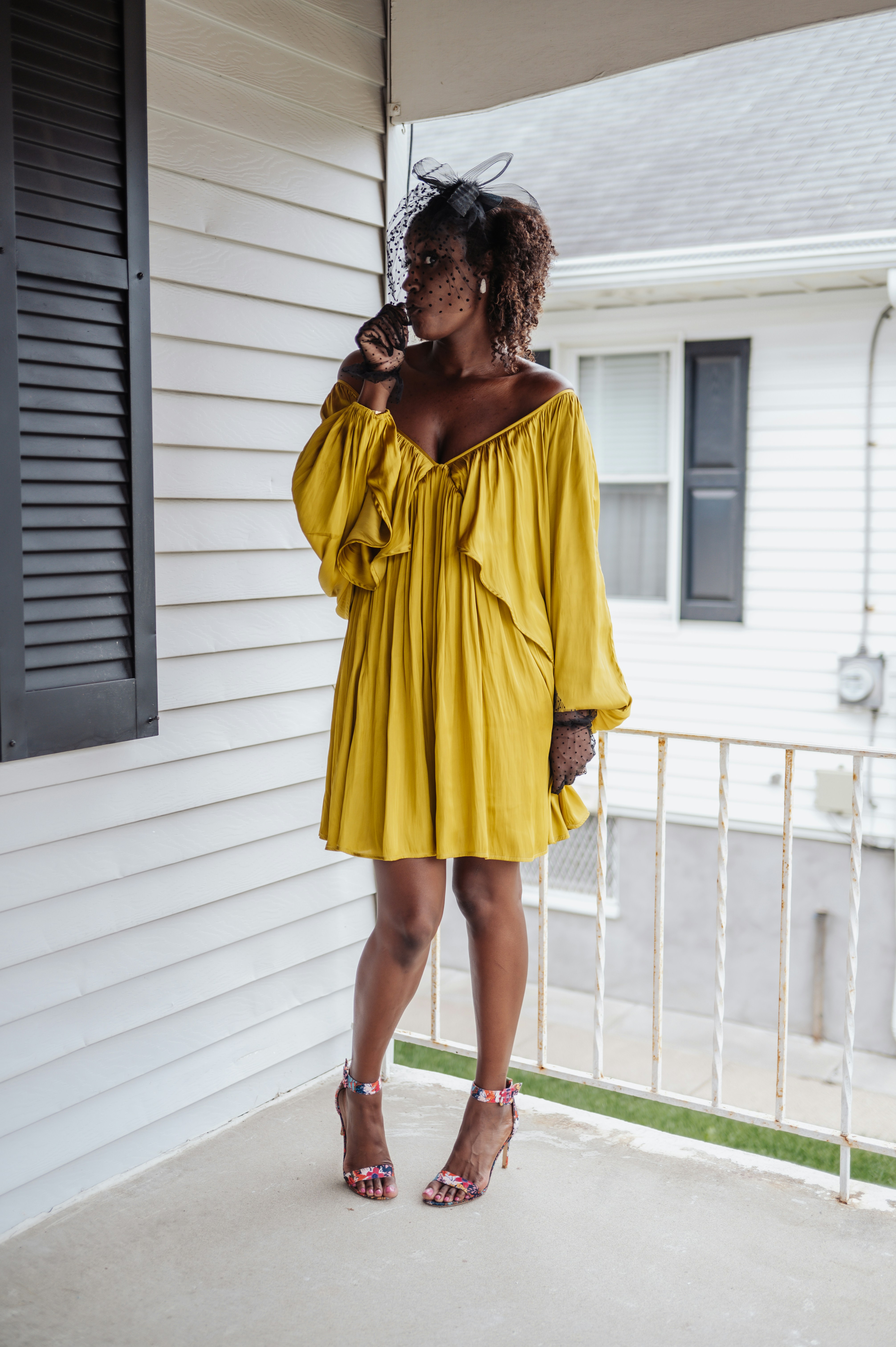 A woman in a yellow dress standing on a porch