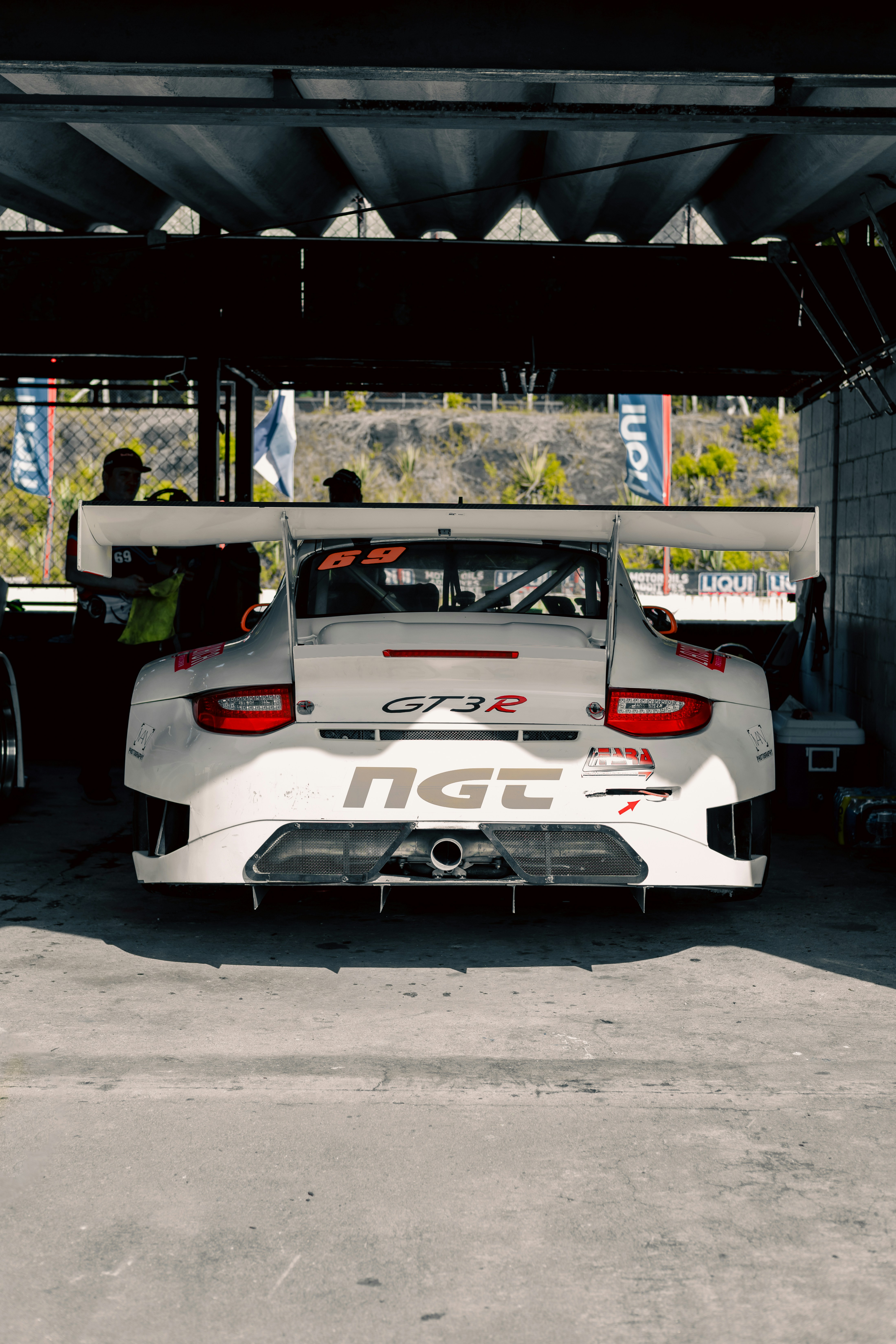 A white car parked in a garage next to another car