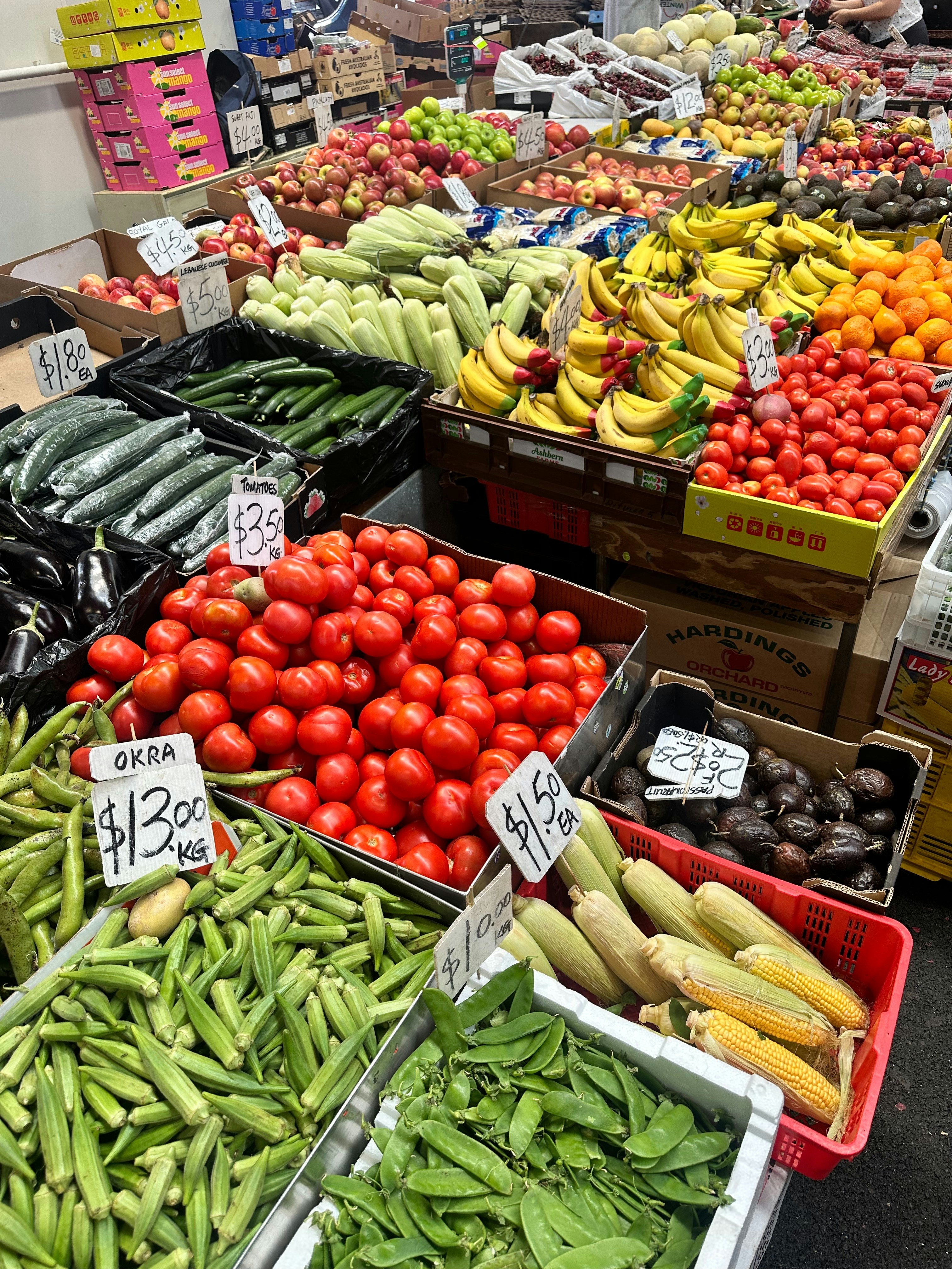 Fresh produce market display with abundant colorful vegetables, tomatoes, peppers, onions, arranged in large baskets at a Ghanaian market, bright natural daylight