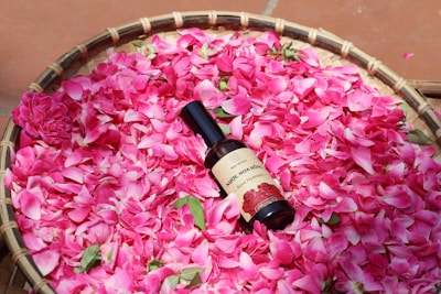 A basket filled with pink flowers and a bottle of wine