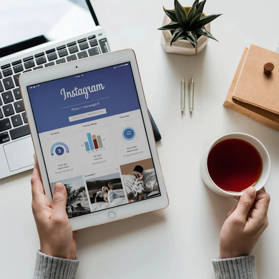 A person holding a tablet next to a cup of tea