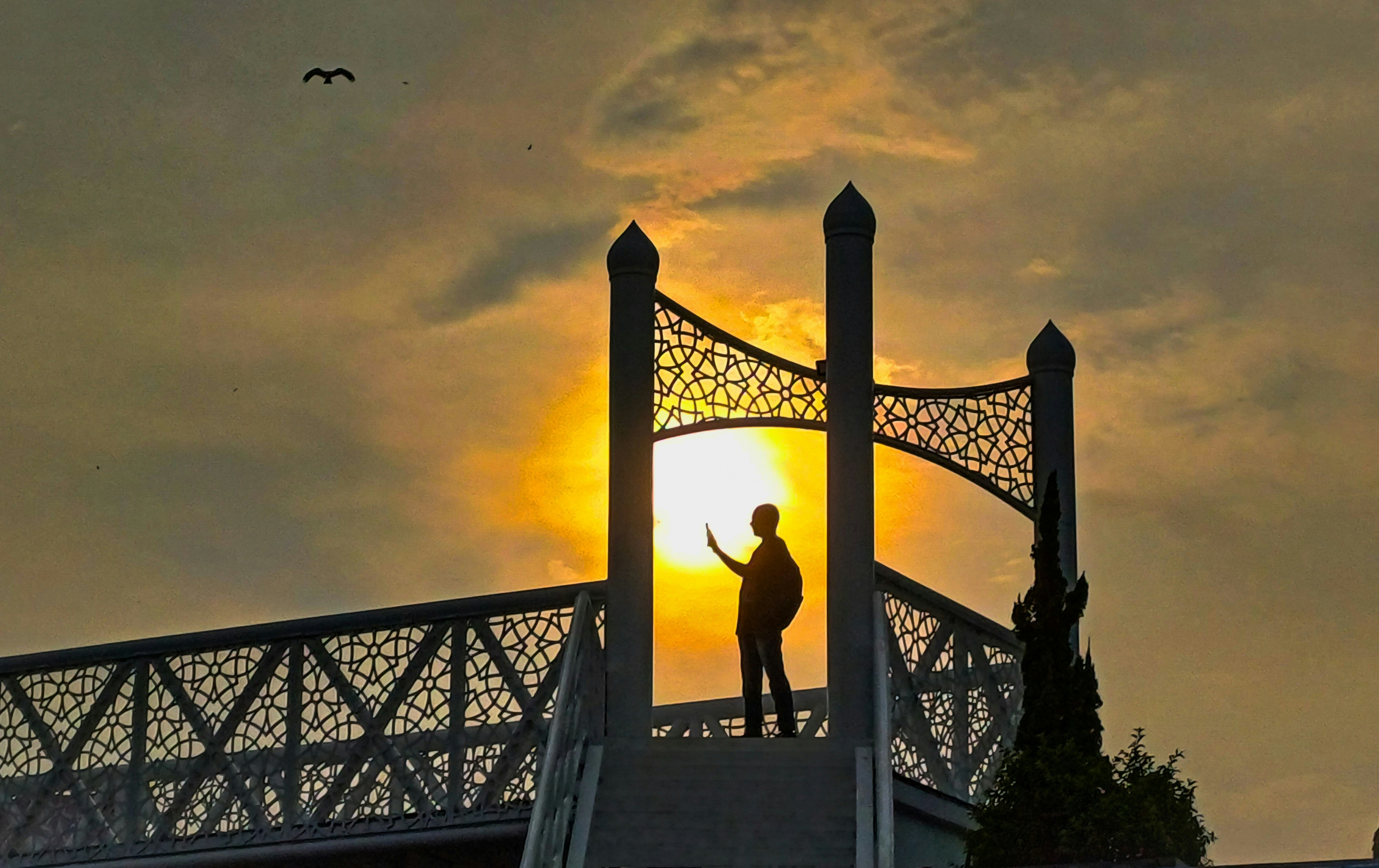 A person standing on a bridge with a sunset in the background