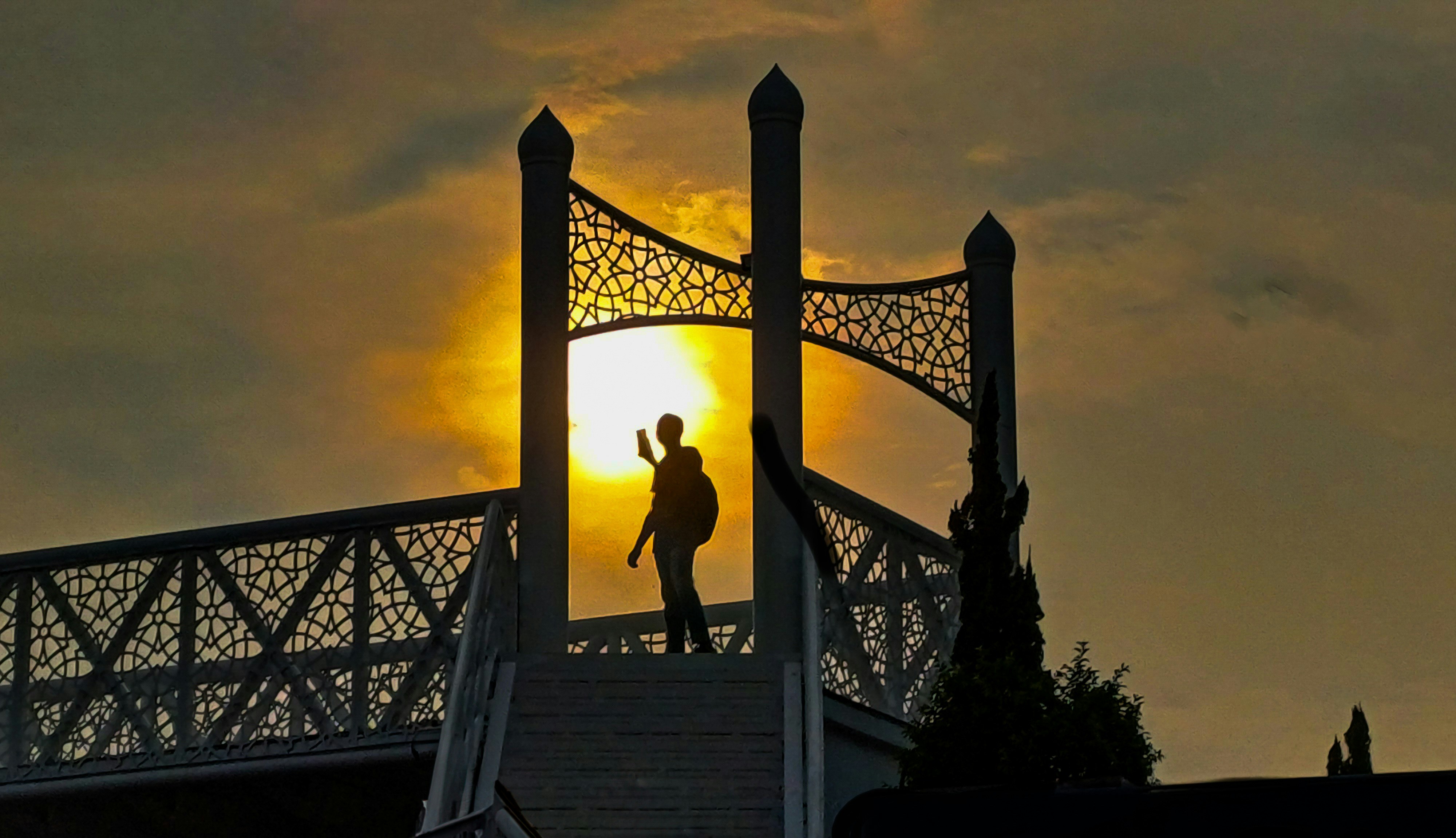 Eine Person, die auf einer Brücke steht, mit der Sonne im Hintergrund