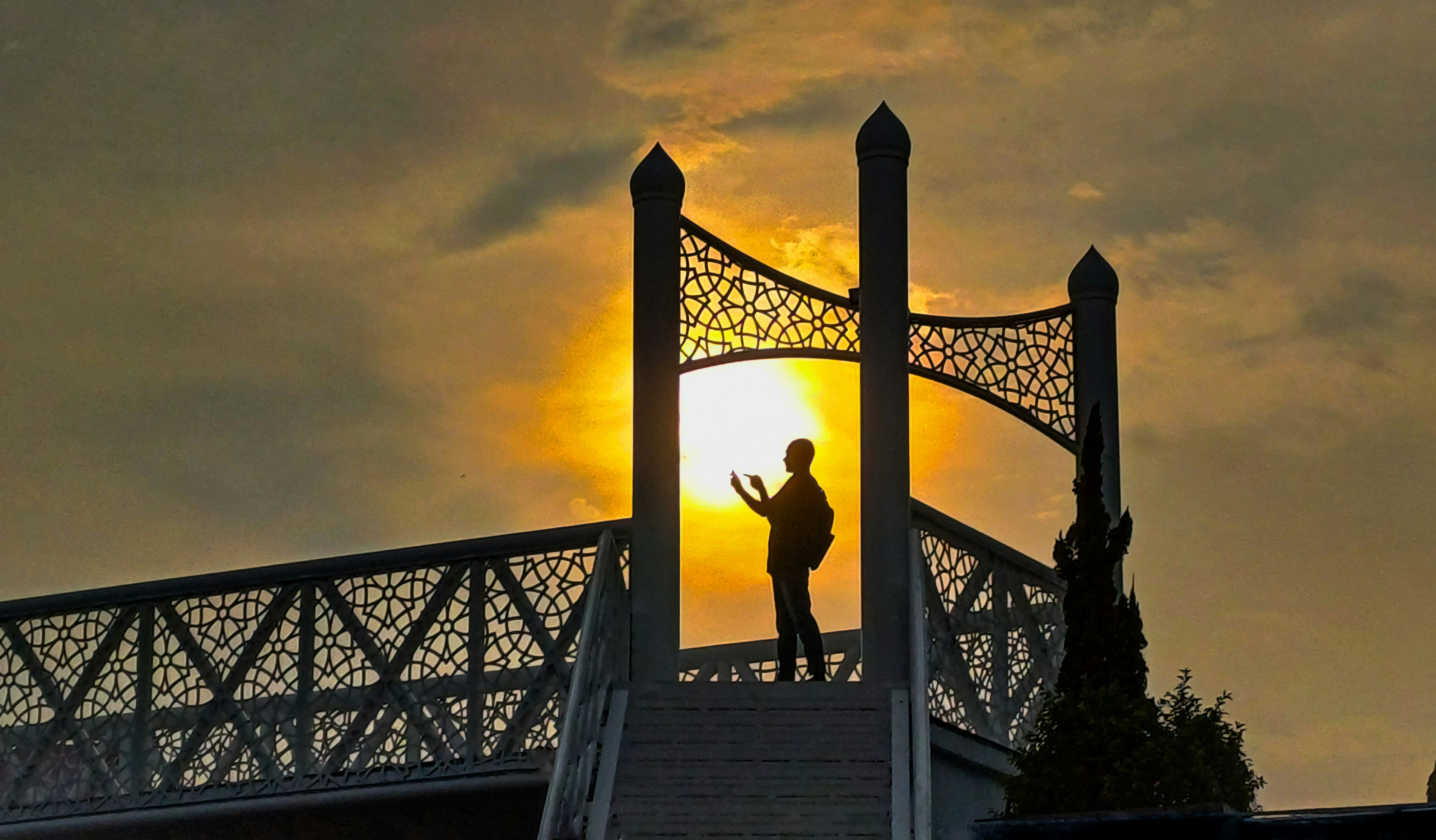 Eine Person, die auf einer Brücke steht, mit der Sonne im Hintergrund