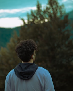 A man standing in front of a forest looking at the sky