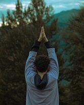 A man standing in front of a forest with his hands in the air