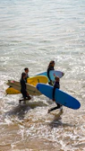 A group of people carrying surfboards into the ocean