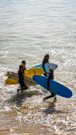 A group of people carrying surfboards into the ocean