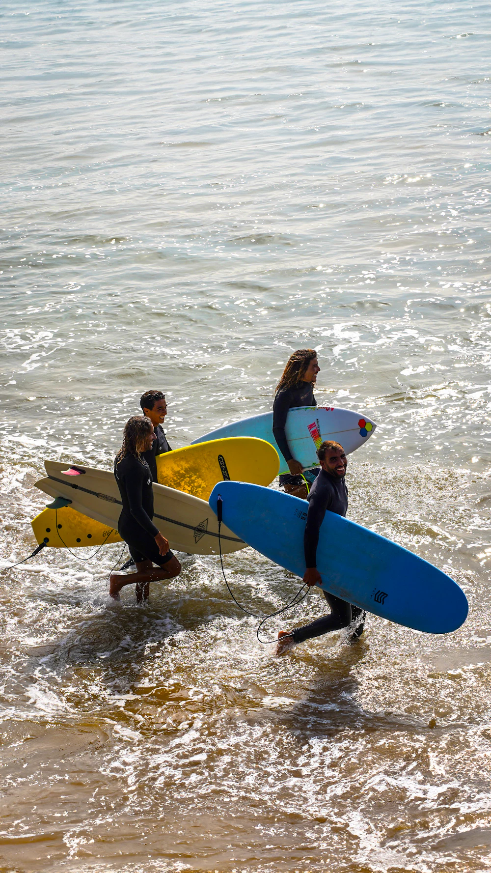 A group carrying surfboards into the ocean