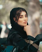 A woman in a black hijab sitting on a car