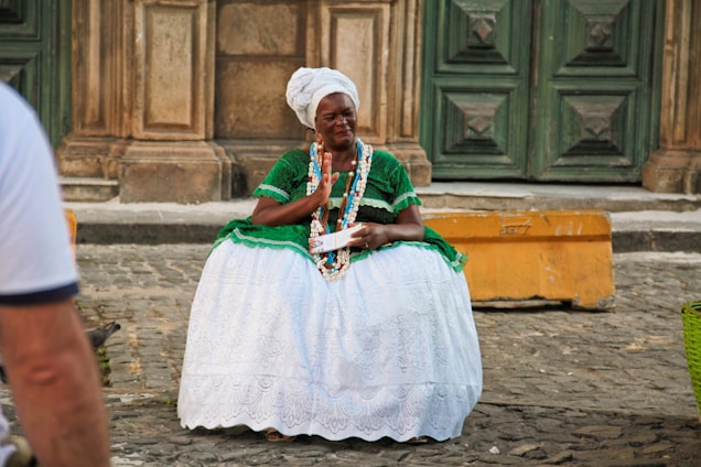A woman in a green and white dress sitting on a bench