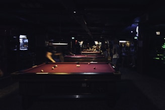 A group of people playing pool in a dark room