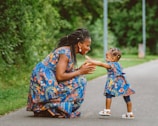 A woman kneeling down next to a little girl