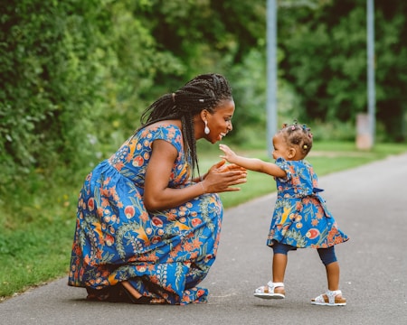 A woman kneeling down next to a little girl