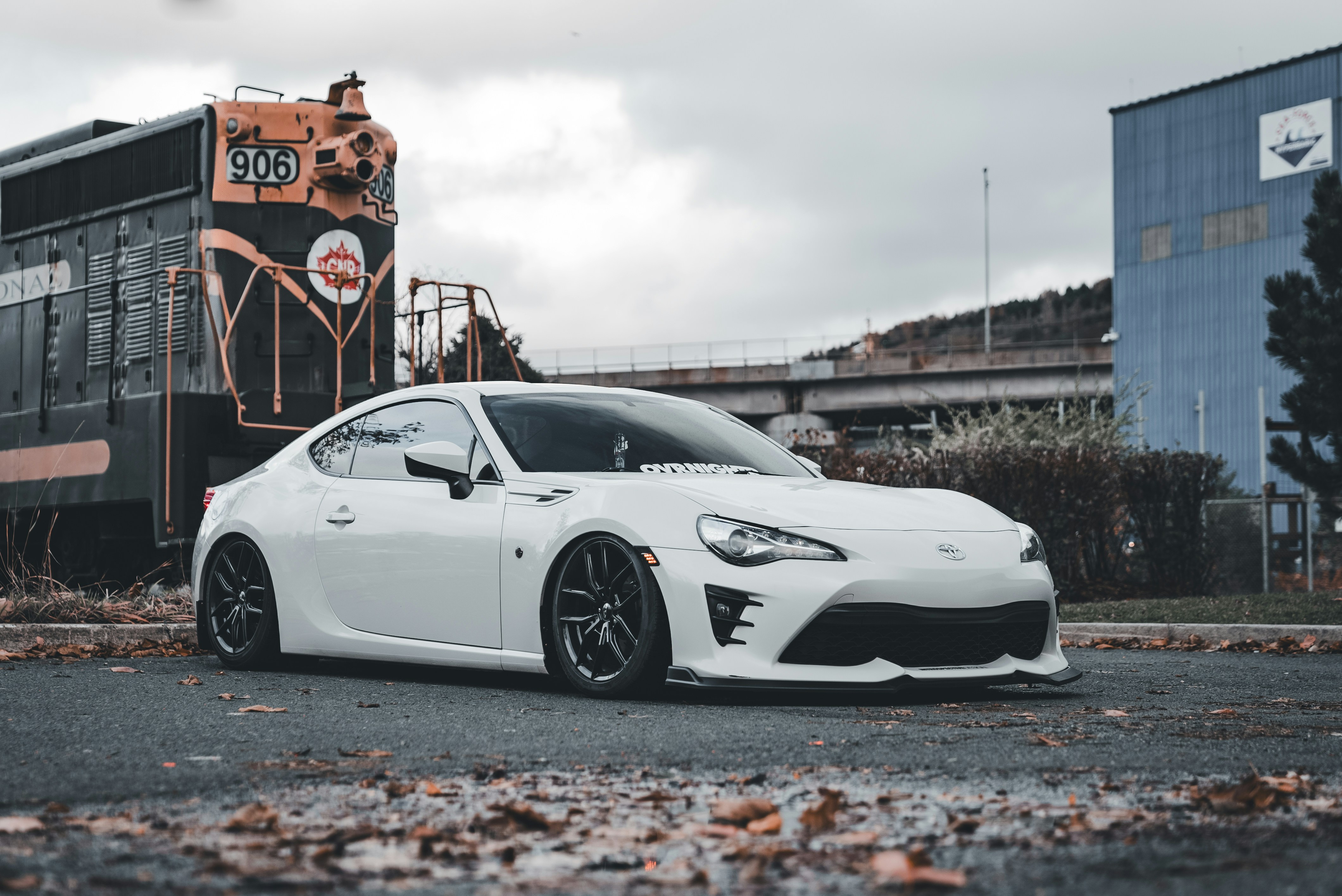 Ein weißer Sportwagen, der vor einem Zug parkt