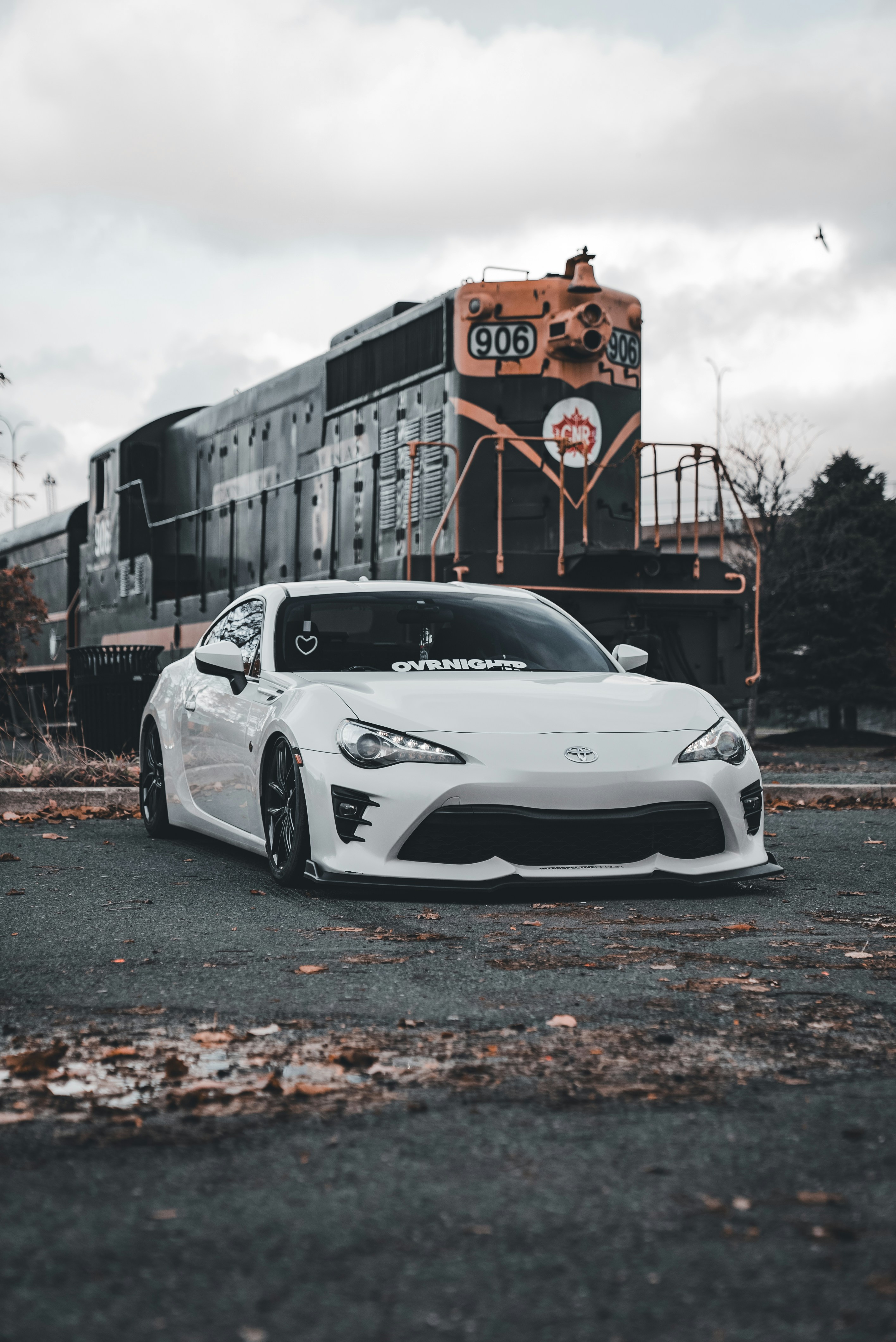 Ein weißer Sportwagen, der vor einem Zug parkt
