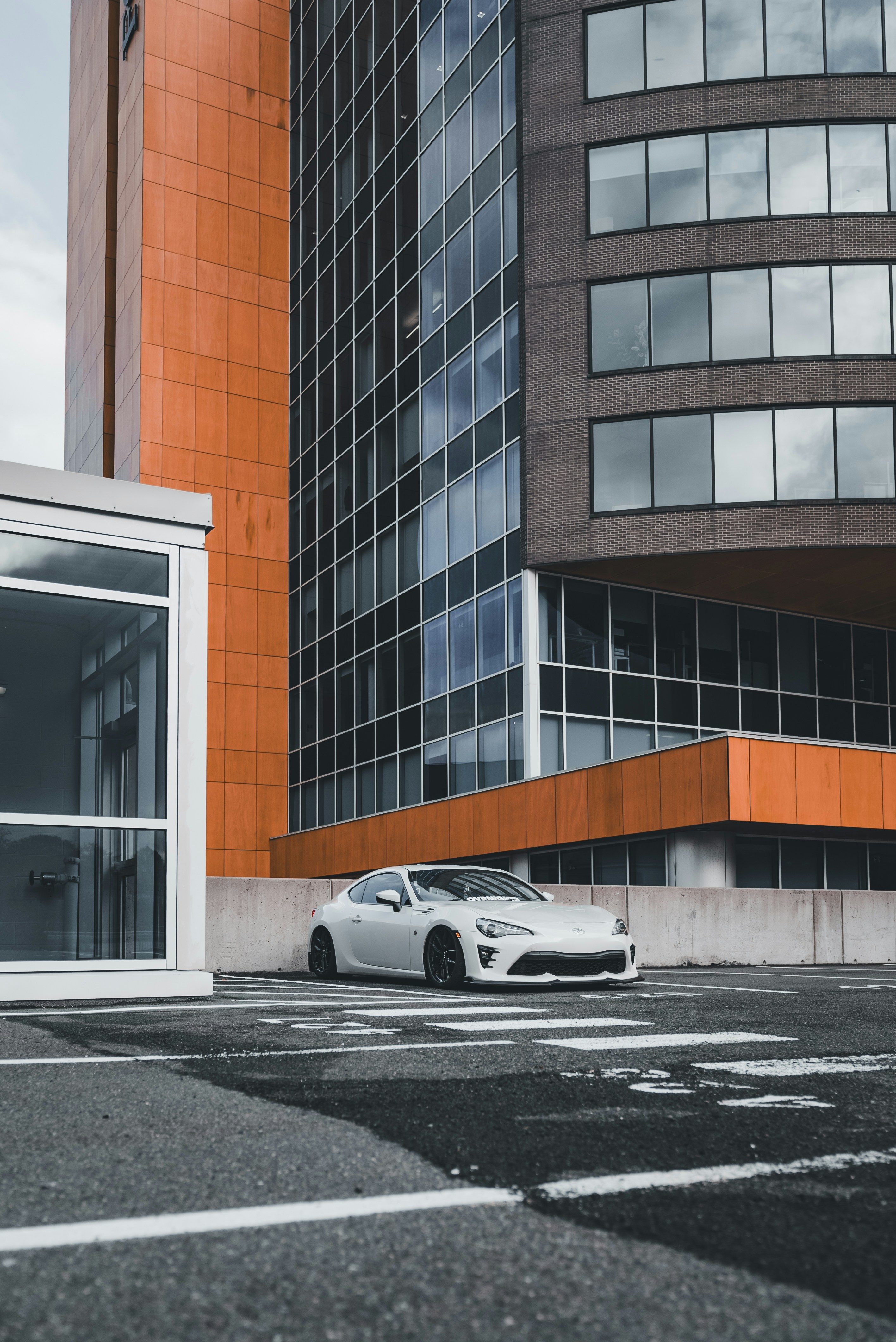 Ein weißes Auto, das vor einem hohen Gebäude geparkt ist