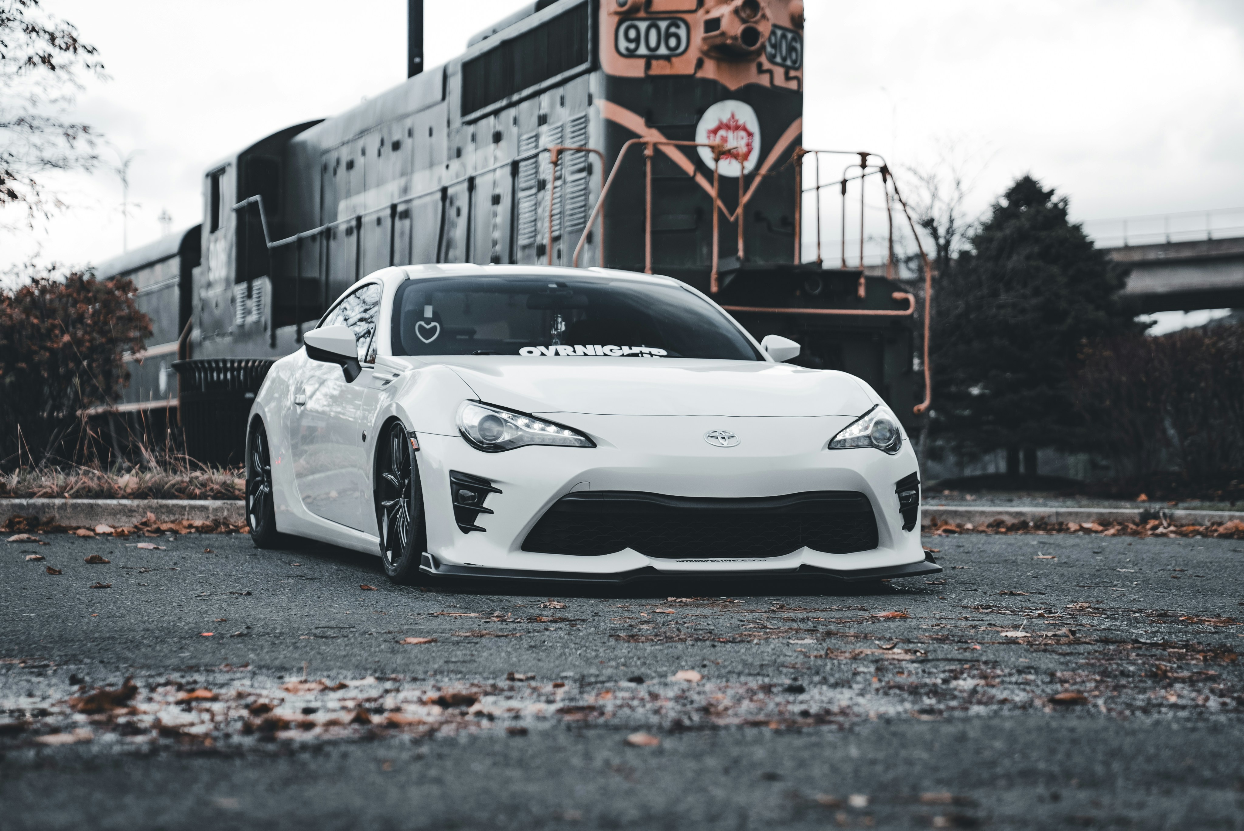 Ein weißer Sportwagen, der vor einem Zug parkt