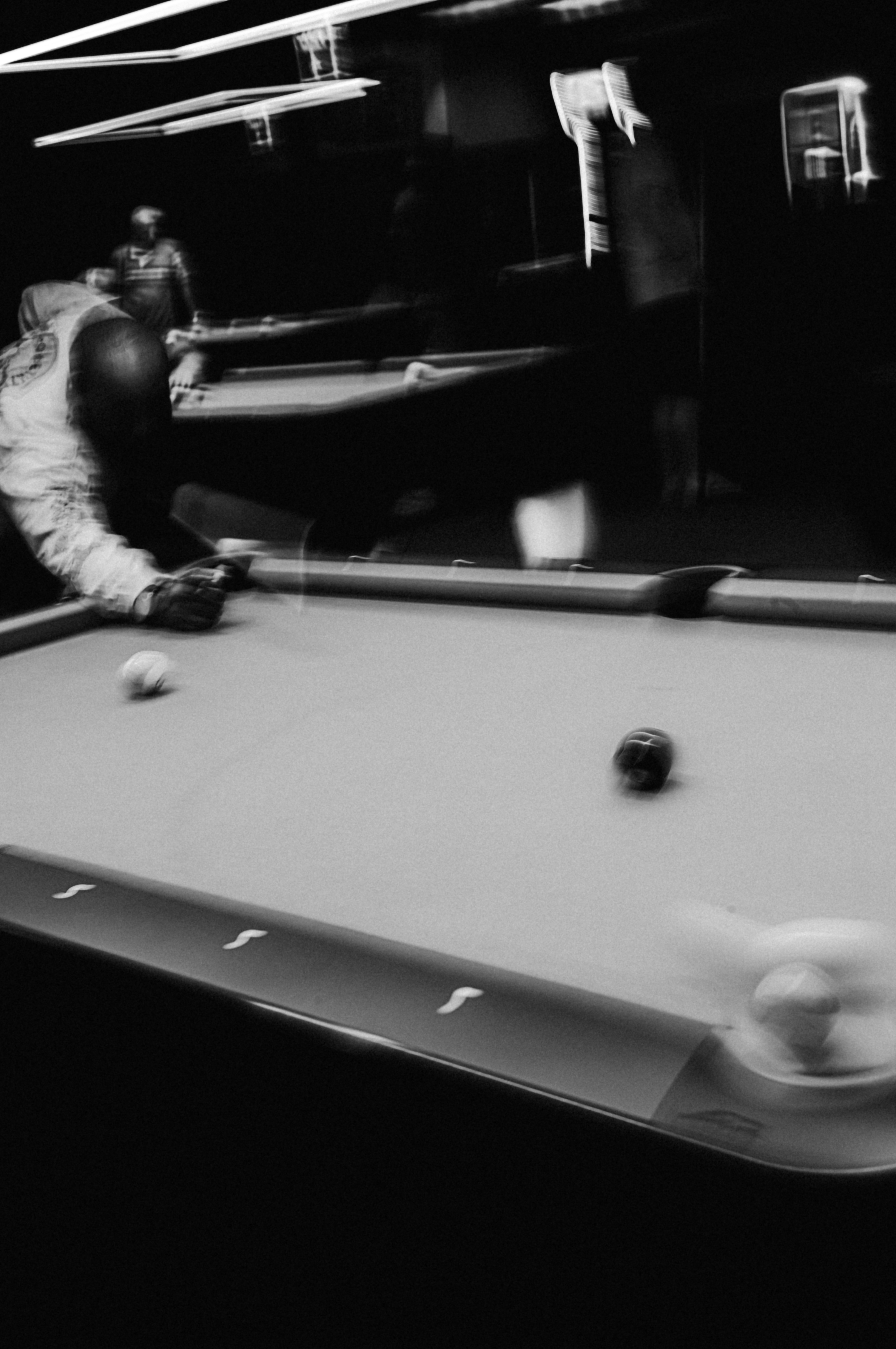 A man is playing pool in a dark room