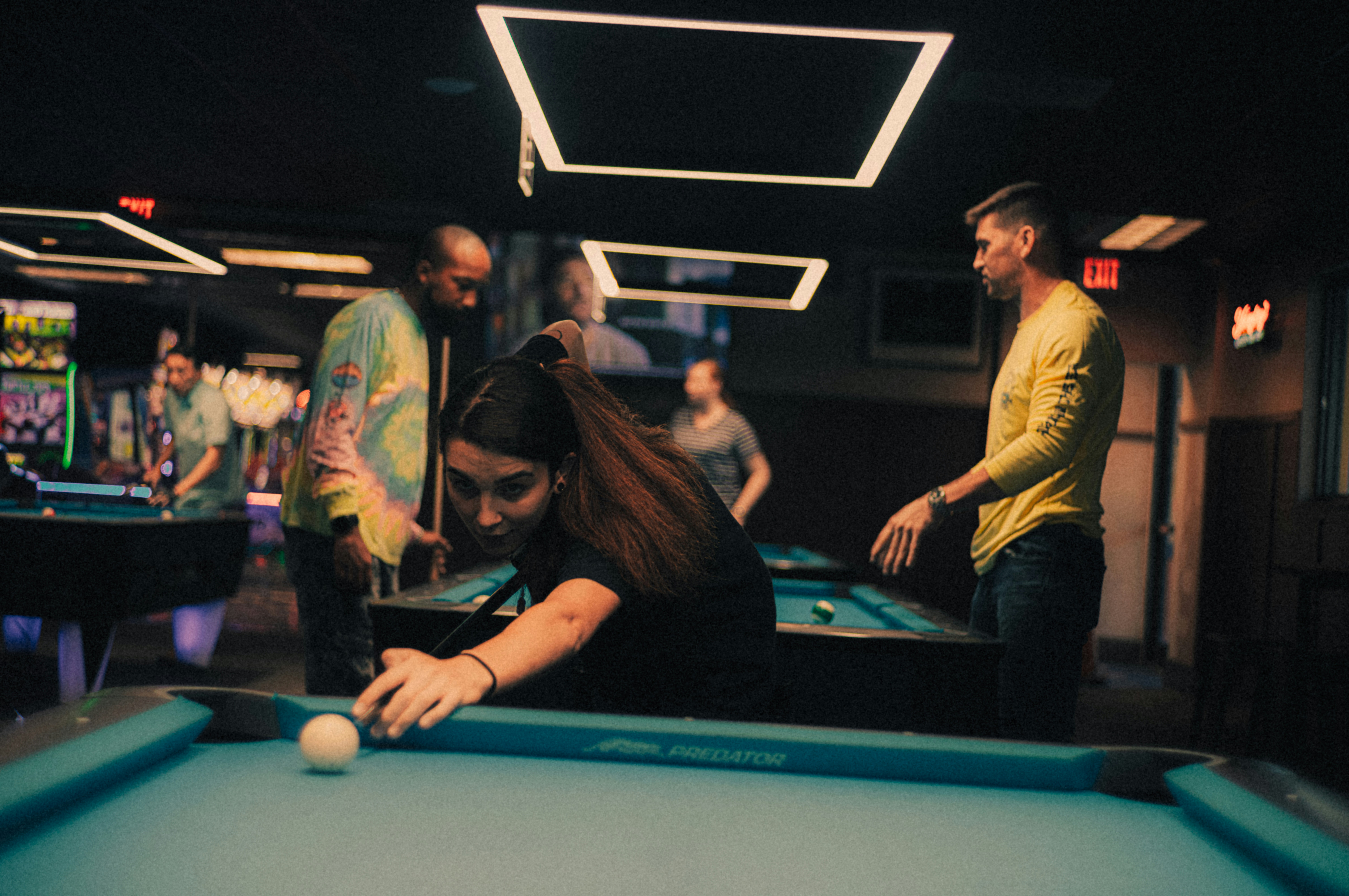patrons playing pool and arcade games at a sports bar