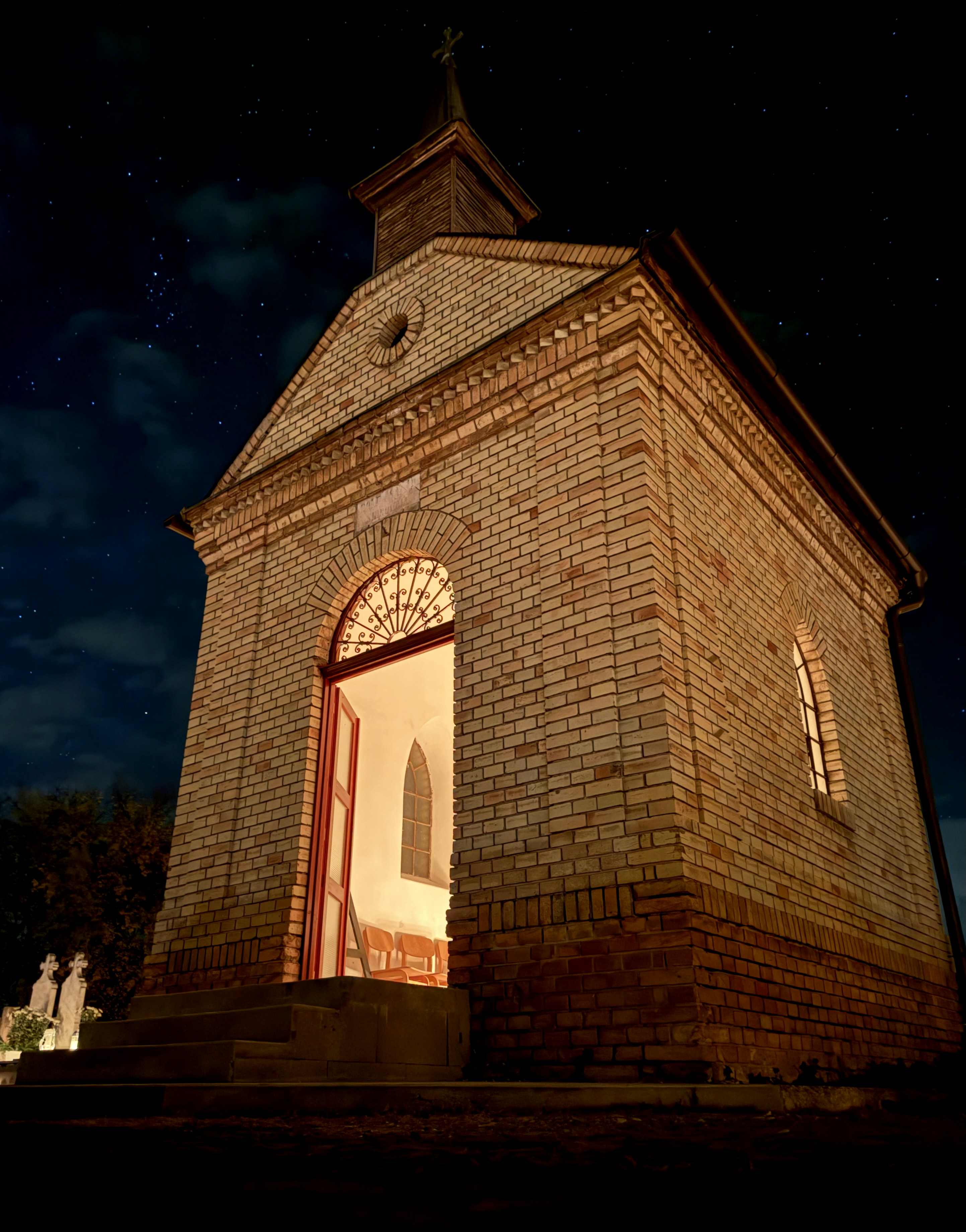 A small brick building with a clock tower at night