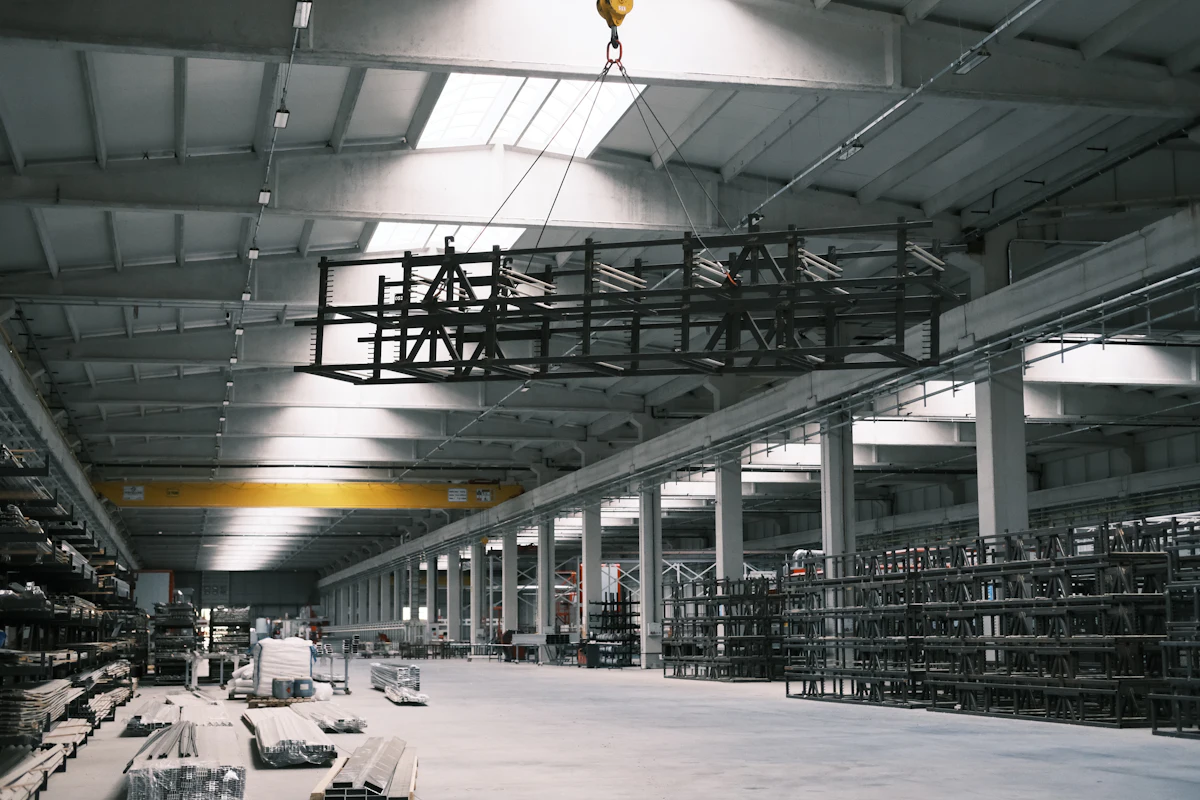 Overhead crane rigging and lifting a steel frame load in a warehouse