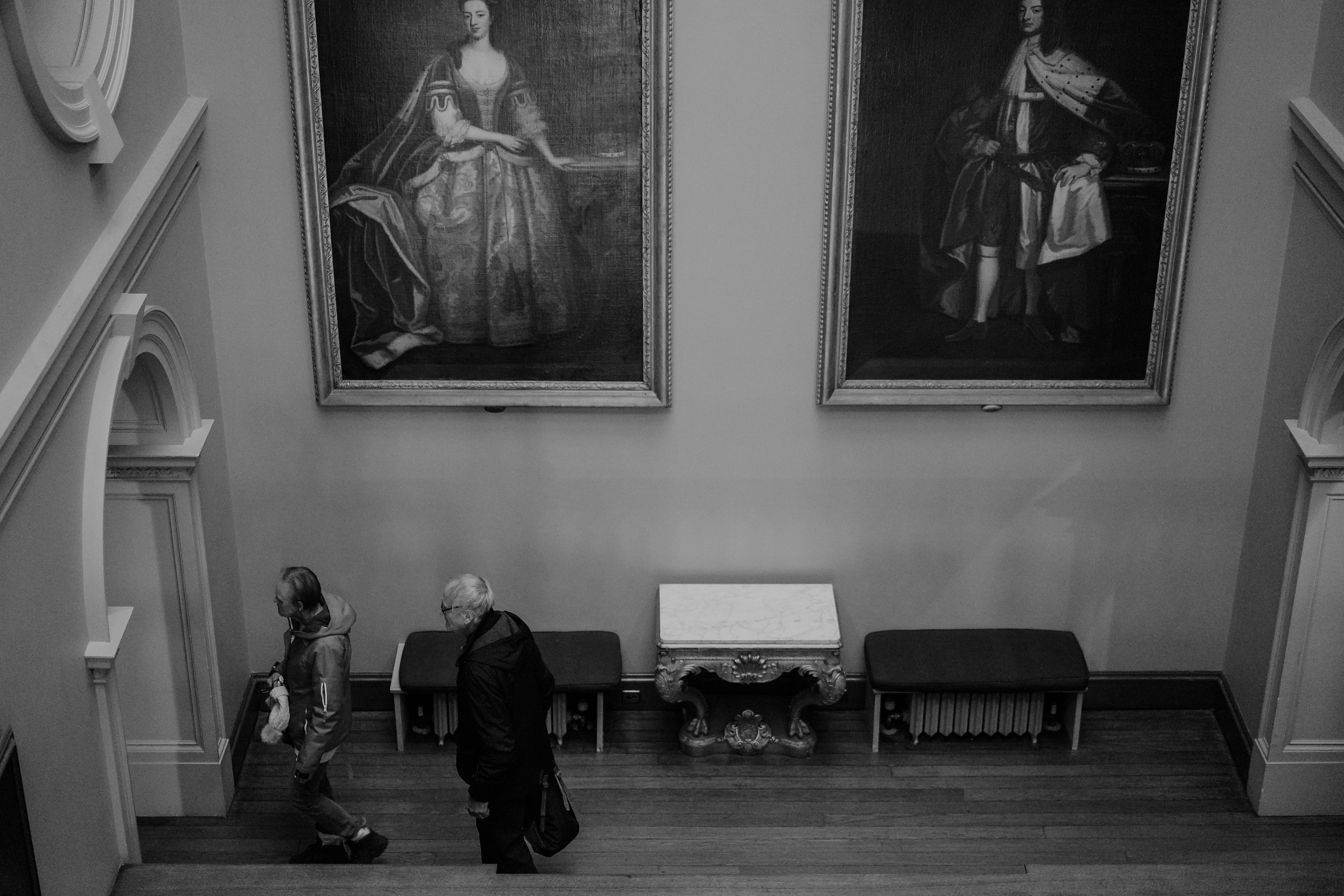 A black and white photo of a man walking down a set of stairs
