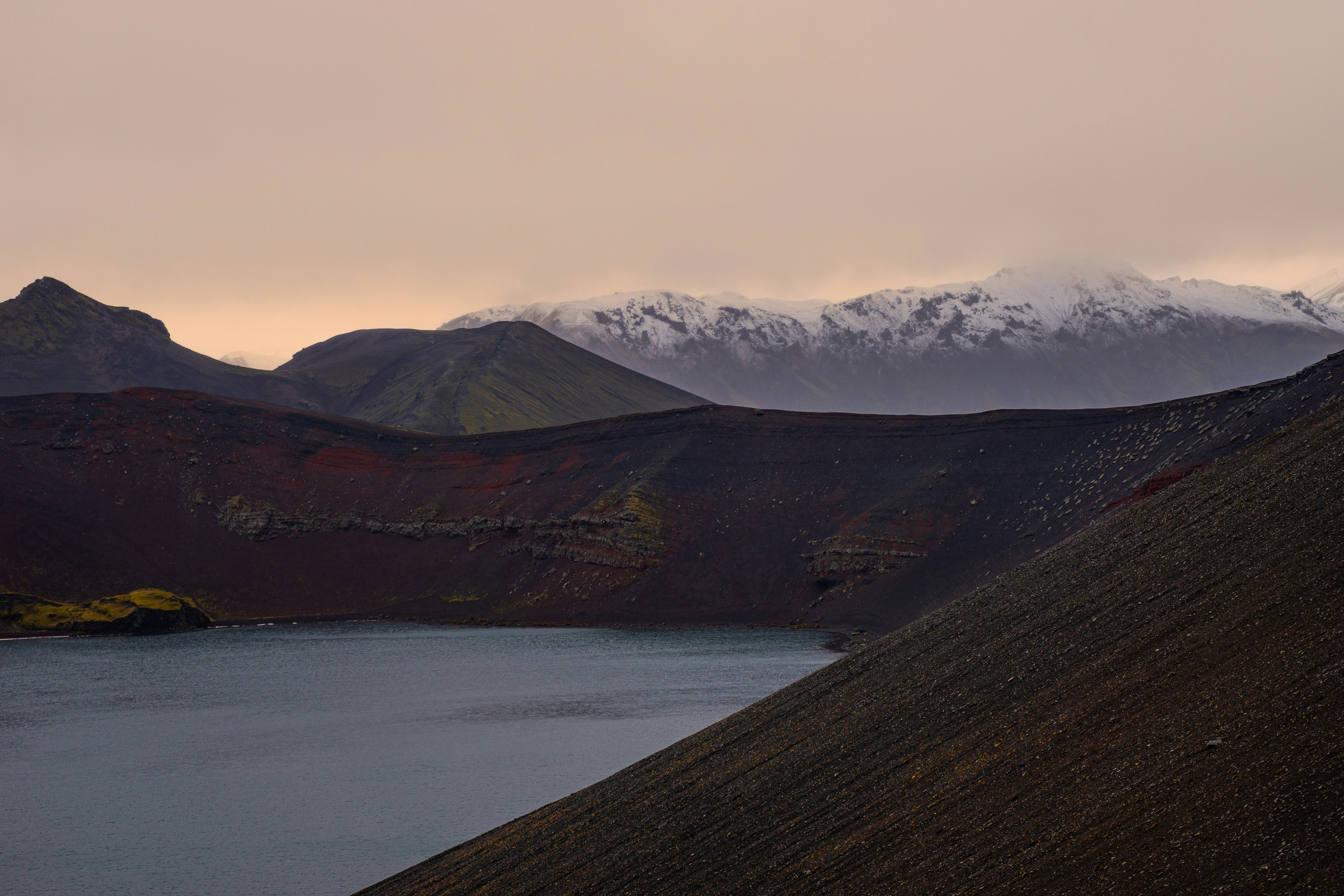 A bird flying over a body of water with mountains in the background