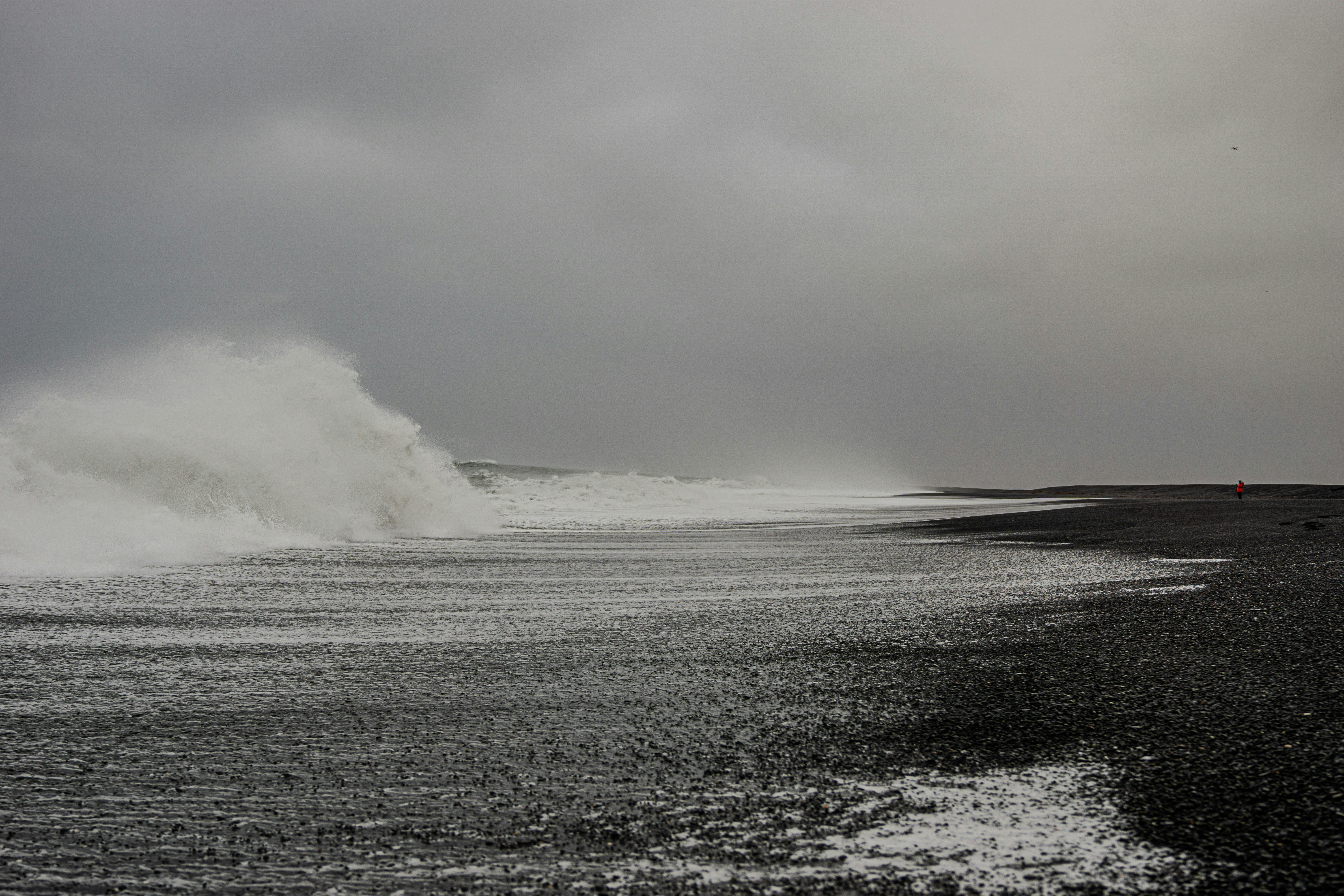 A large wave crashing into the ocean on a cloudy day
