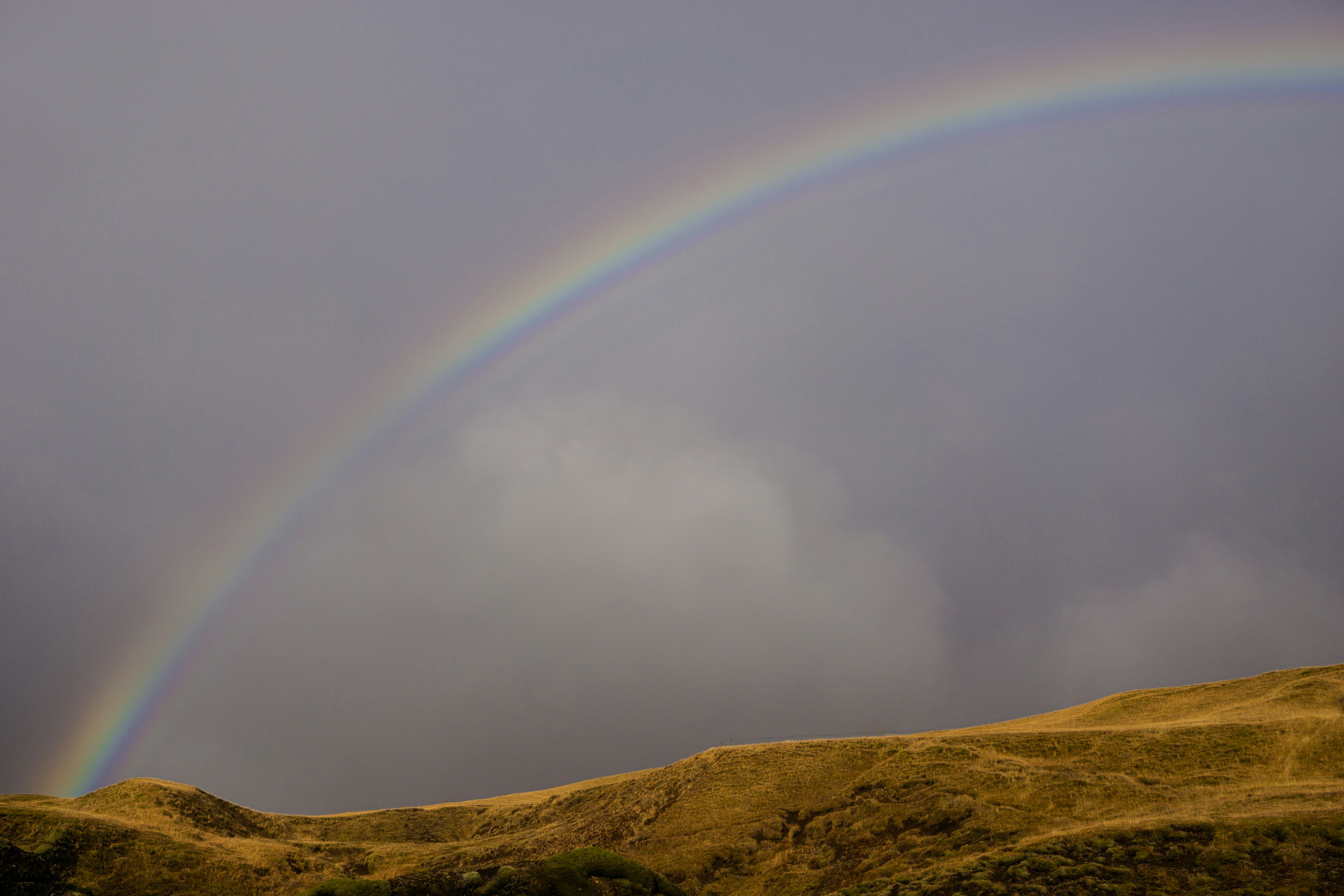 A double rainbow in the sky over a hill