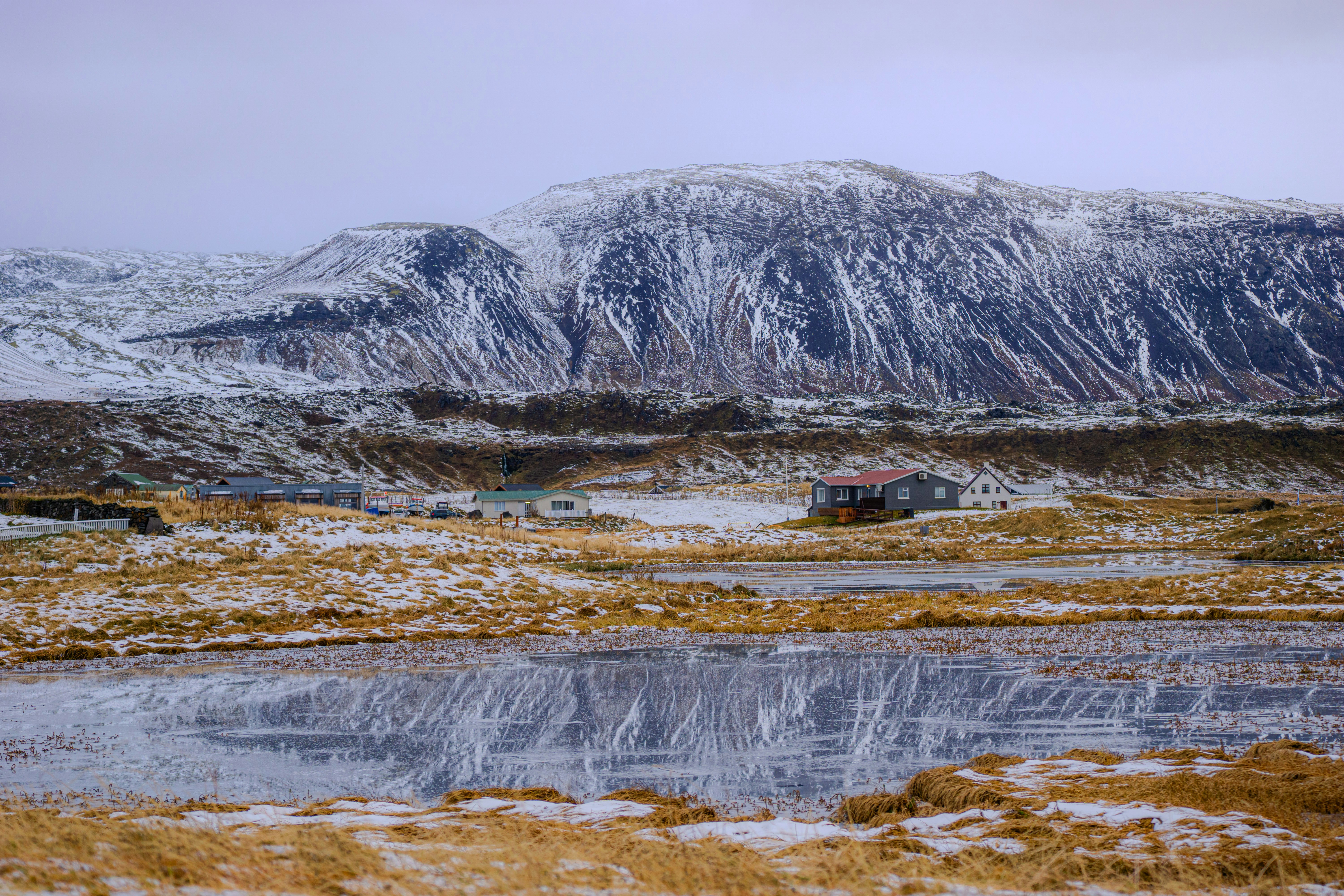 A snow covered mountain with a lake in the foreground