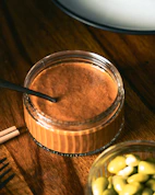 A wooden table topped with a jar of chocolate pudding