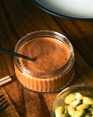 A wooden table topped with a jar of chocolate pudding