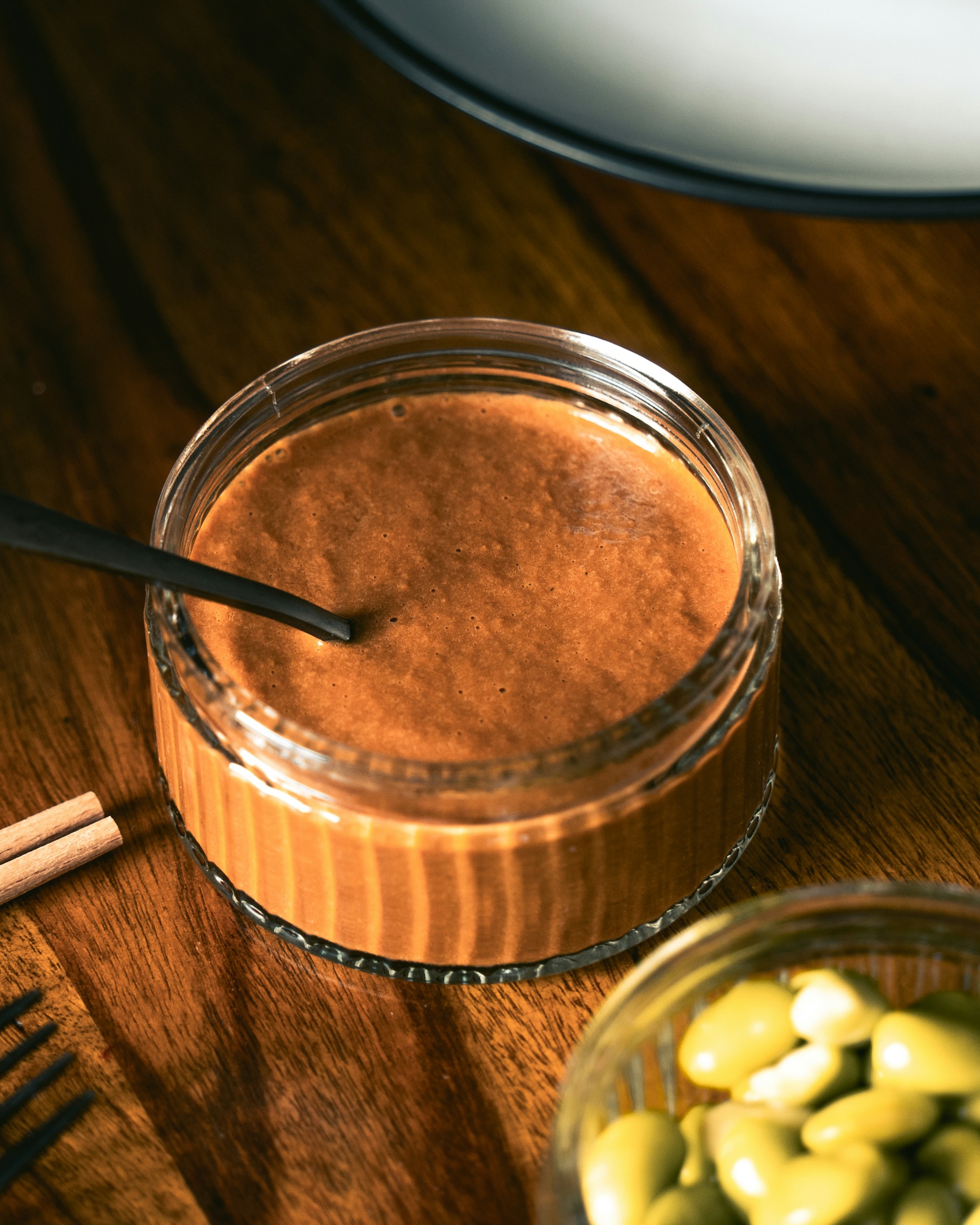 A wooden table topped with a jar of chocolate pudding