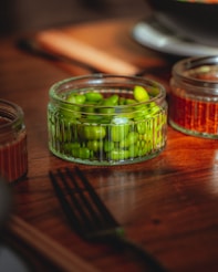 A wooden table topped with jars filled with green beans