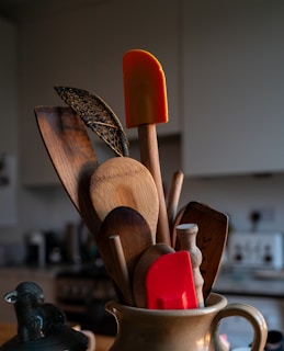 A cup filled with wooden utensils on top of a table