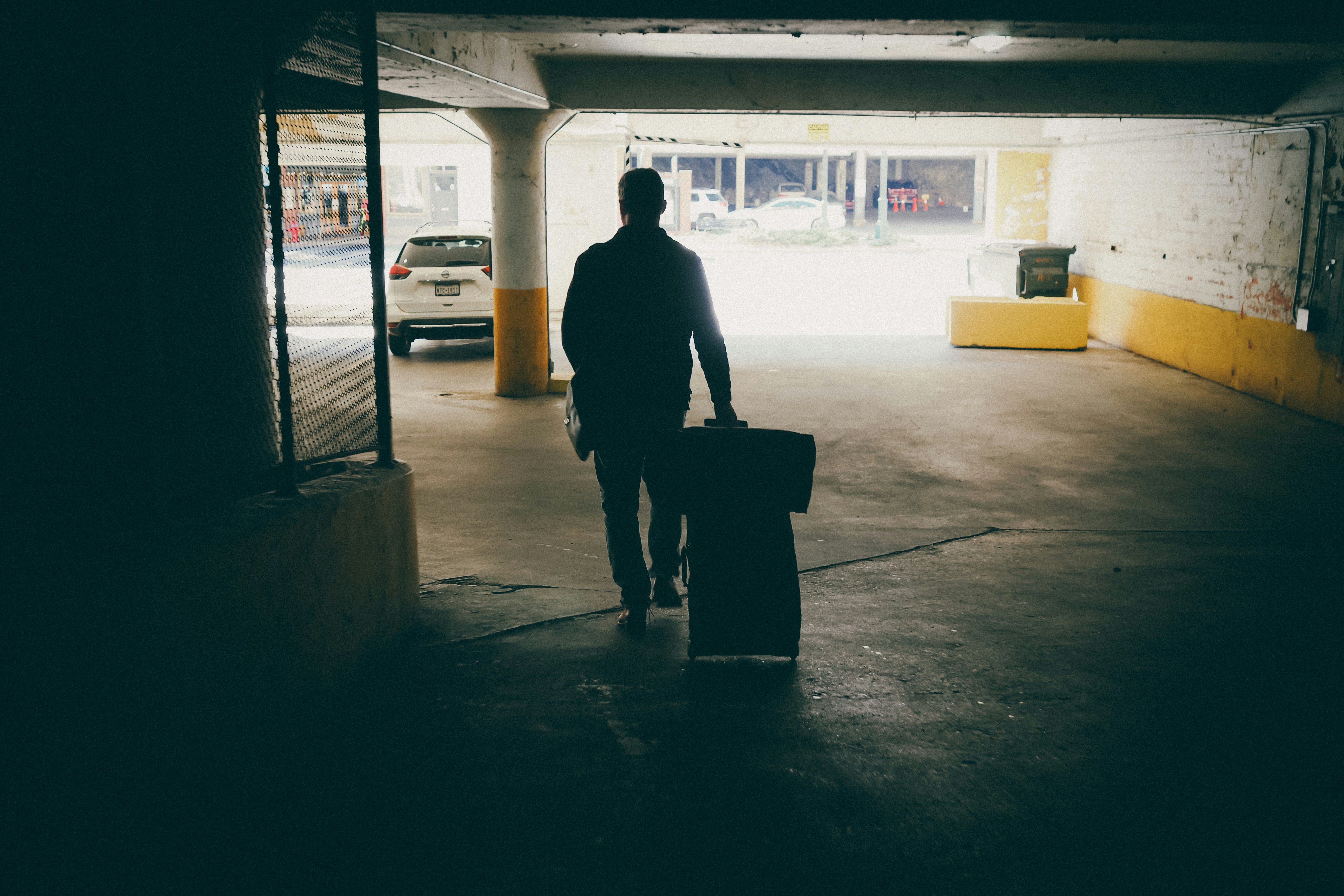 A man with a suitcase walking into a parking garage