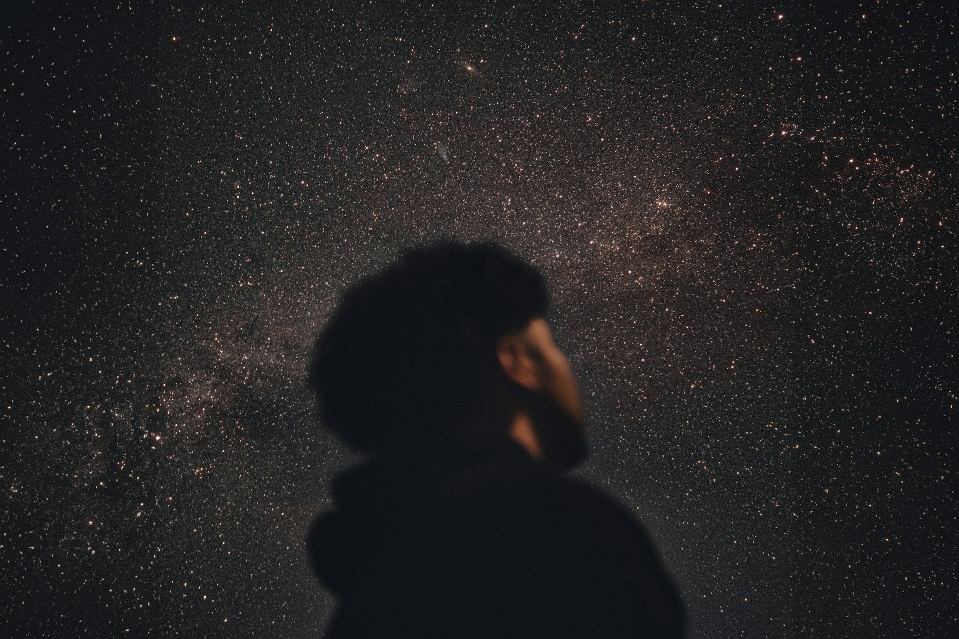 A man standing in the dark looking up at the stars