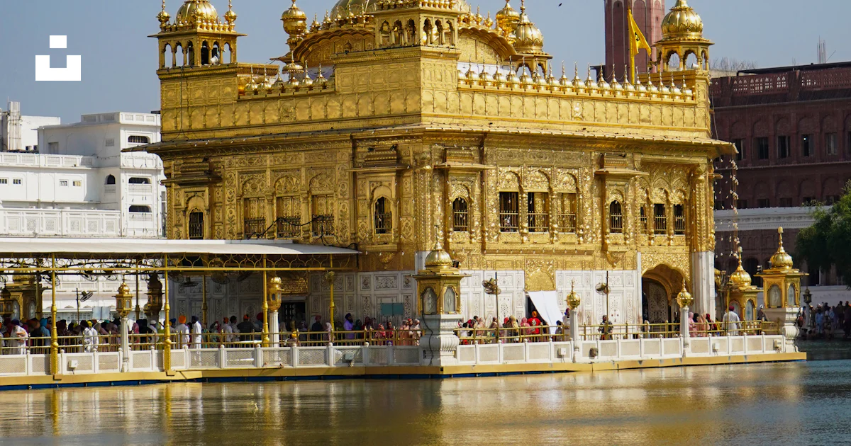 A large golden building sitting next to a body of water photo – Free ...
